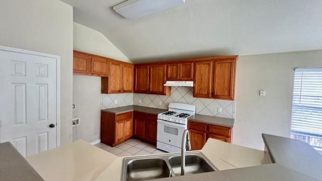 kitchen with under cabinet range hood, lofted ceiling, white range with gas stovetop, and a wealth of natural light
