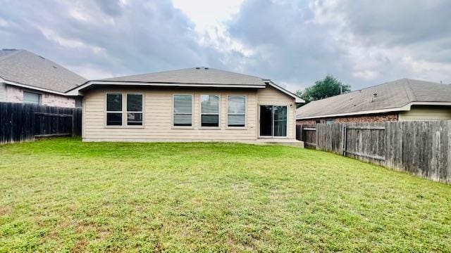 rear view of property with a fenced backyard and a yard