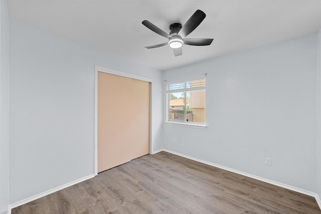 unfurnished bedroom featuring baseboards, a ceiling fan, a closet, and wood finished floors