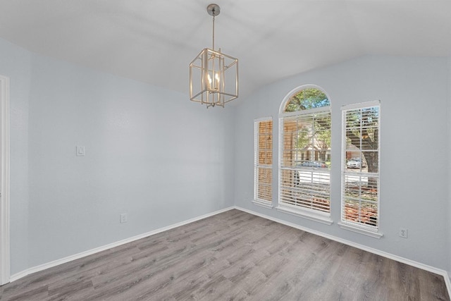 unfurnished dining area with baseboards, vaulted ceiling, wood finished floors, and an inviting chandelier