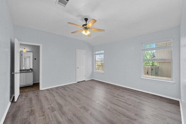unfurnished bedroom featuring baseboards, visible vents, multiple windows, and wood finished floors