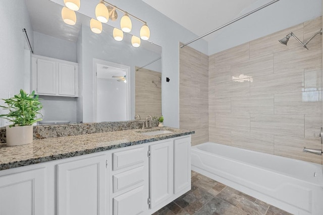 bathroom with a ceiling fan, stone finish flooring, tub / shower combination, and vanity
