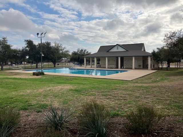community pool with a lawn, fence, and a patio
