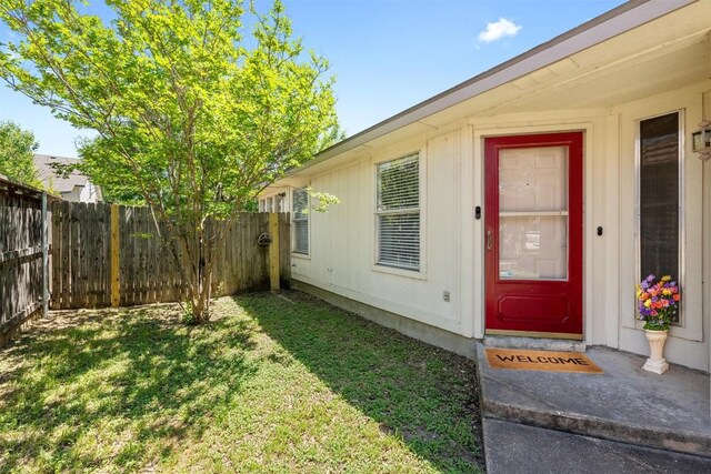 doorway to property with a lawn and fence