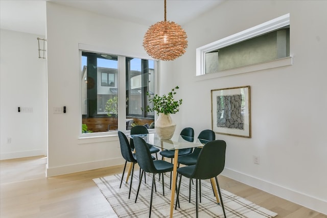 dining room featuring baseboards, an inviting chandelier, and light wood-style floors