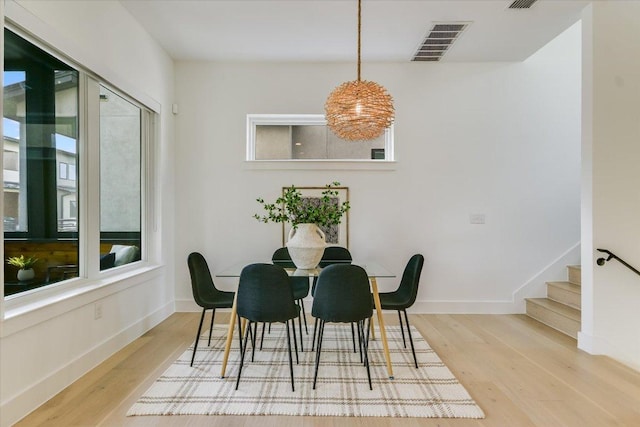 dining area featuring stairs, baseboards, visible vents, and wood finished floors
