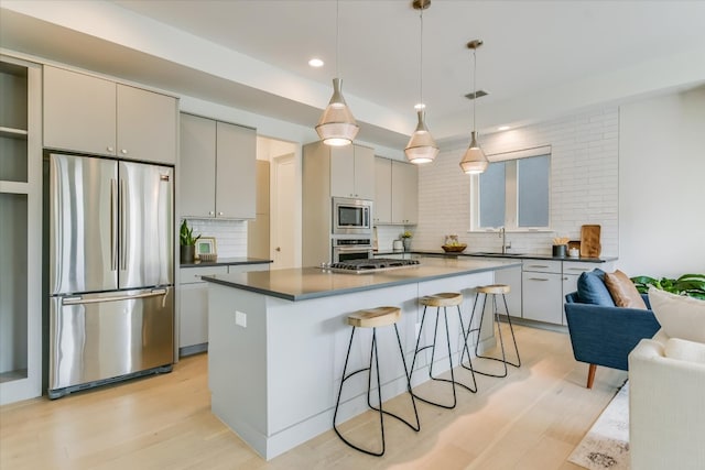 kitchen featuring decorative backsplash, a kitchen breakfast bar, recessed lighting, light wood-style flooring, and appliances with stainless steel finishes