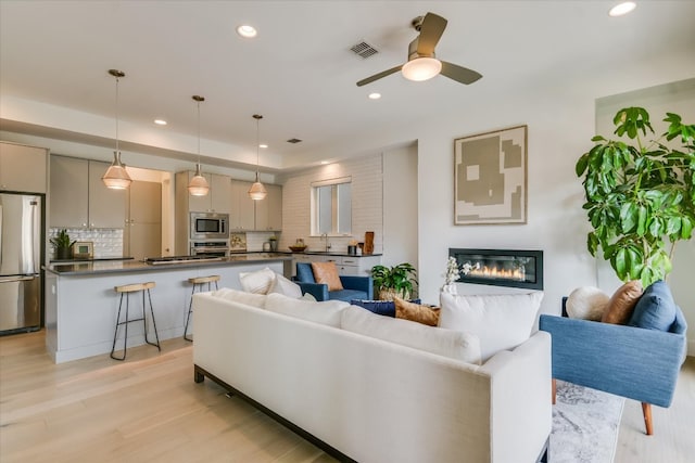 living area featuring recessed lighting, a ceiling fan, and light wood finished floors