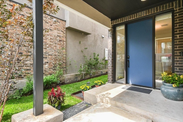 view of exterior entry with brick siding and visible vents