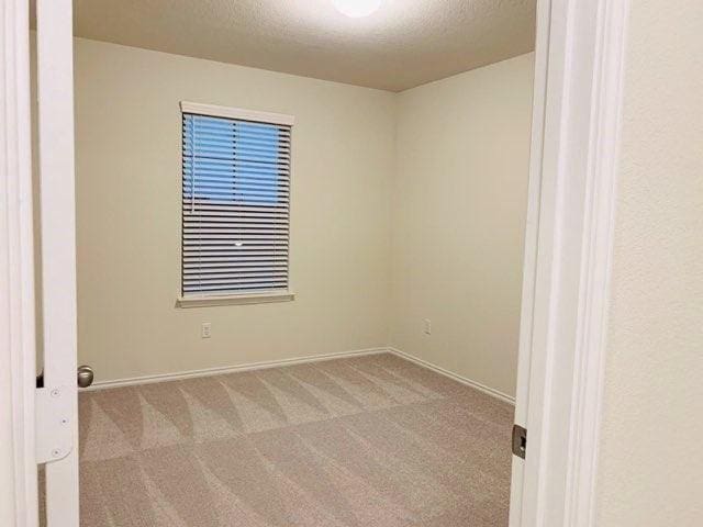 carpeted empty room with baseboards and a textured ceiling