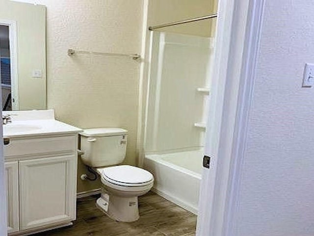 full bathroom featuring a textured wall, toilet, vanity, wood finished floors, and tub / shower combination