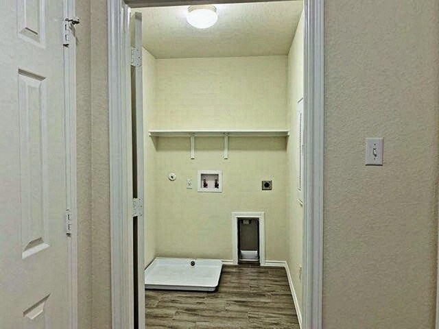 241 Cascata Way, Liberty Hill, TX 78642 - washroom featuring hookup for an electric dryer, wood finished floors, washer hookup, gas dryer hookup, and a textured wall