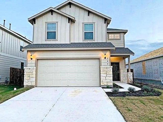 view of front facade with stone siding, an attached garage, concrete driveway, and board and batten siding