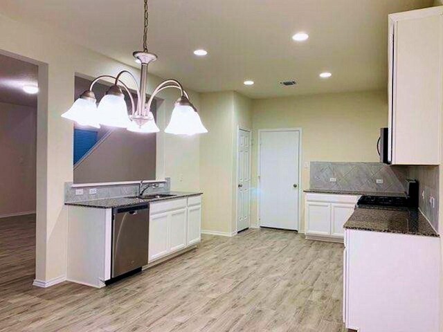 241 Cascata Way, Liberty Hill, TX 78642 - kitchen featuring stainless steel appliances, white cabinets, a sink, baseboards, and recessed lighting