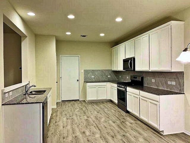 kitchen with stainless steel appliances, a sink, recessed lighting, light wood-style flooring, and tasteful backsplash