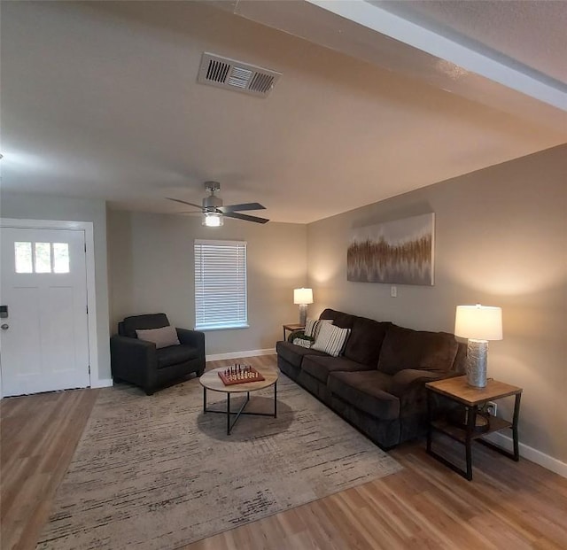 living area featuring a ceiling fan, baseboards, visible vents, and wood finished floors