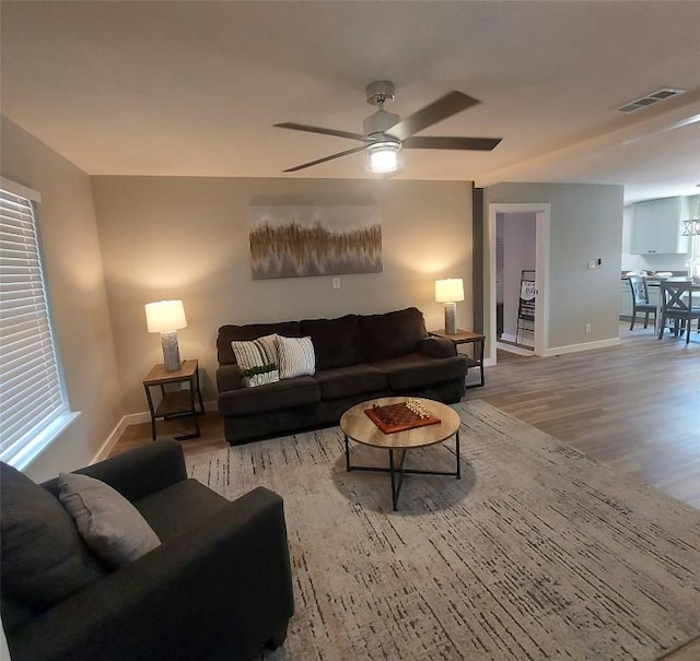 living area featuring visible vents, a ceiling fan, baseboards, and wood finished floors