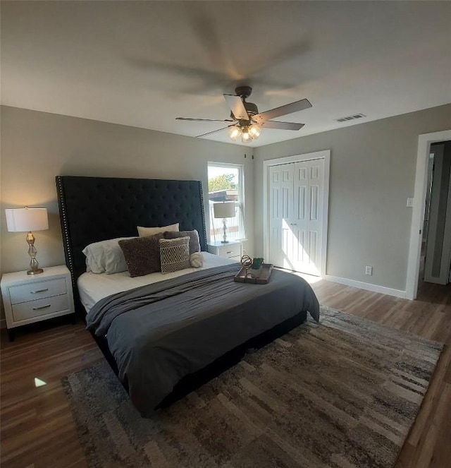 bedroom with visible vents, a closet, wood finished floors, baseboards, and a ceiling fan