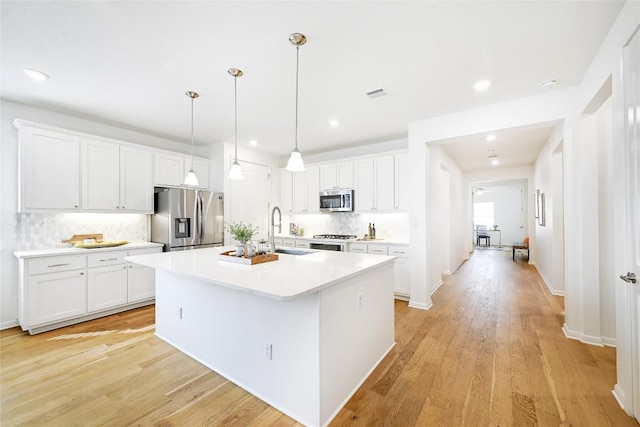 19020 Fernando Trl, Austin, TX 78738 - kitchen with appliances with stainless steel finishes, a sink, decorative backsplash, an island with sink, and white cabinetry