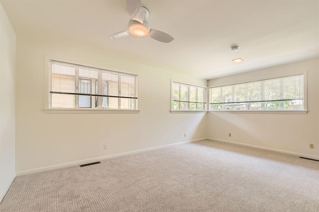 carpeted empty room with visible vents, a ceiling fan, and baseboards