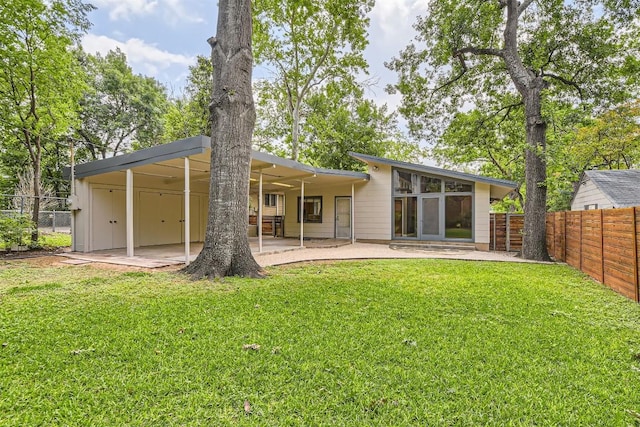 rear view of property featuring a lawn, a patio, and a fenced backyard
