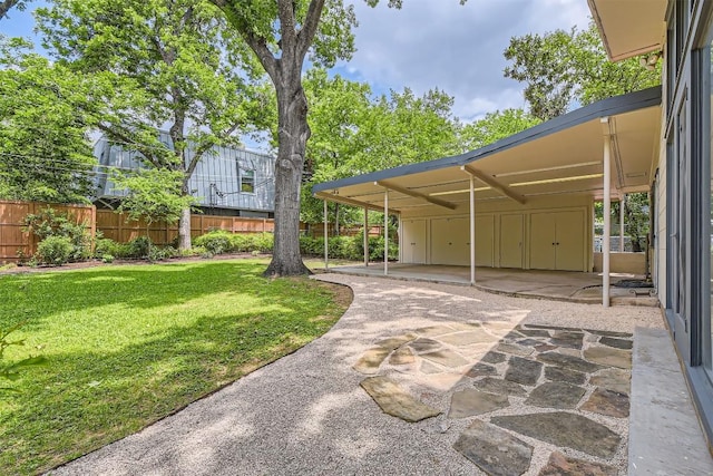 view of property's community featuring a patio area, fence, a yard, and a carport