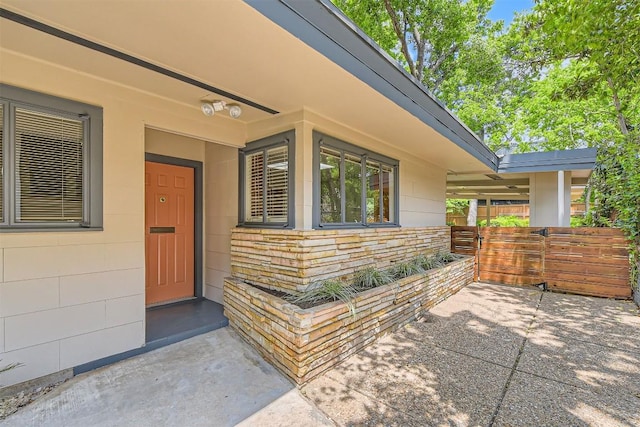 doorway to property with a patio, fence, and stone siding