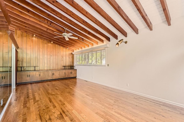 unfurnished room featuring baseboards, ceiling fan, lofted ceiling with beams, and wood finished floors