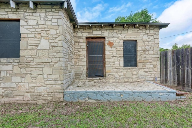 exterior space featuring fence and stone siding