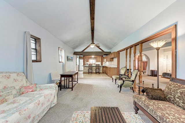 living room with vaulted ceiling with beams, arched walkways, ceiling fan, and light carpet