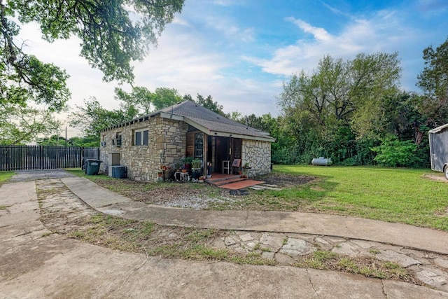 back of property featuring a lawn, fence, central air condition unit, and stone siding