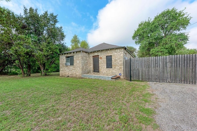 view of property exterior featuring a lawn, fence, and stone siding