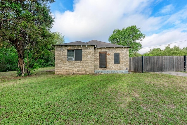 back of house featuring a lawn, fence, stone siding, and cooling unit