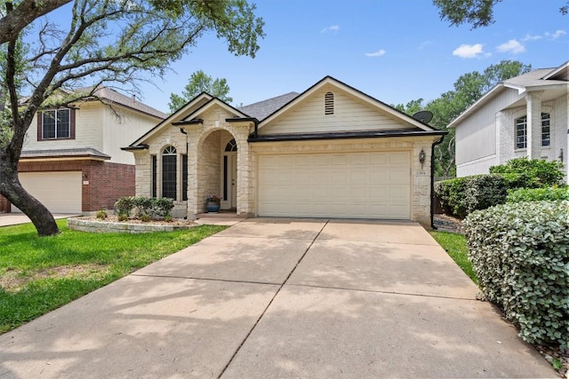 view of front facade with a shingled roof, an attached garage, driveway, and stone siding