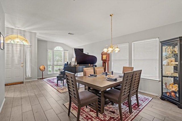 dining room with a chandelier, visible vents, baseboards, lofted ceiling, and light wood-style flooring