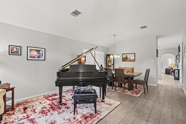 sitting room with visible vents, arched walkways, light wood finished floors, and a notable chandelier