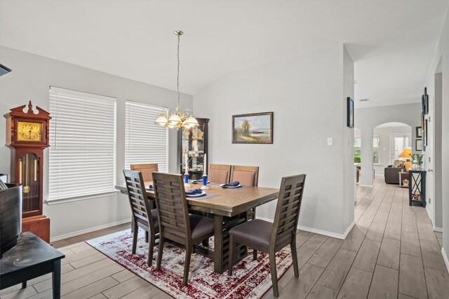 12804 Council Bluff Dr, Austin, TX 78727 - dining area featuring light wood-style flooring, arched walkways, a chandelier, baseboards, and vaulted ceiling