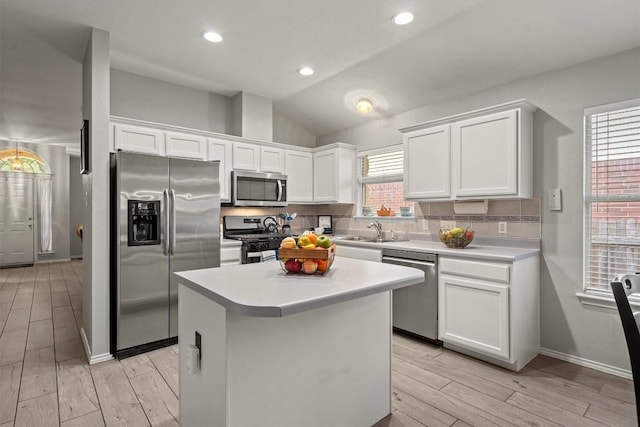 kitchen featuring appliances with stainless steel finishes, tasteful backsplash, light countertops, light wood-style floors, and white cabinetry