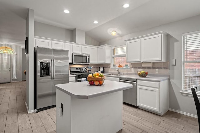 kitchen featuring appliances with stainless steel finishes, tasteful backsplash, light countertops, white cabinets, and light wood finished floors