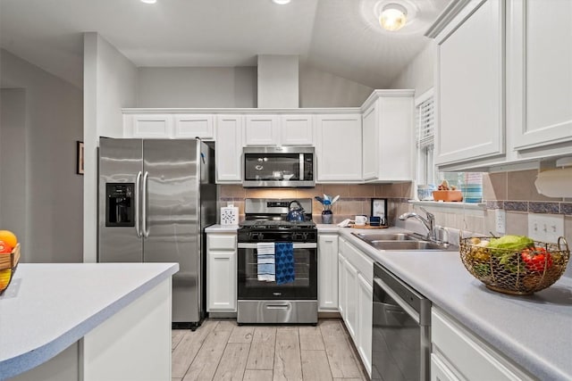 kitchen featuring a sink, appliances with stainless steel finishes, white cabinets, and light countertops