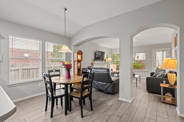 dining room with plenty of natural light, arched walkways, and light wood-style flooring