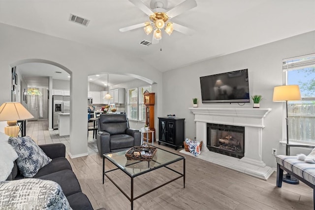 living room featuring arched walkways, a ceiling fan, and visible vents