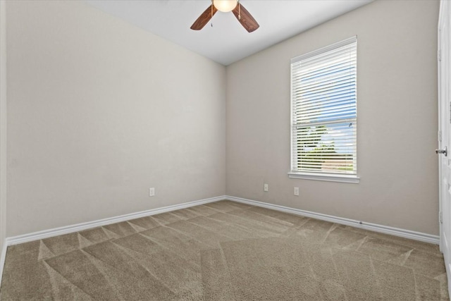 carpeted spare room with a ceiling fan and baseboards