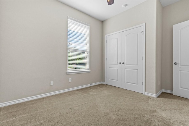 unfurnished bedroom featuring baseboards, ceiling fan, carpet, and a closet