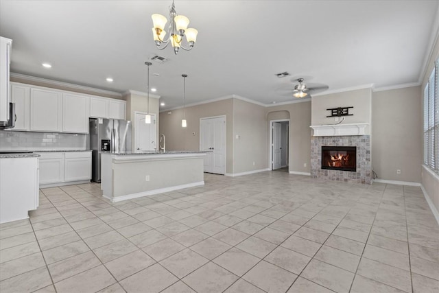 kitchen with stainless steel refrigerator with ice dispenser, open floor plan, light tile patterned flooring, and ceiling fan with notable chandelier