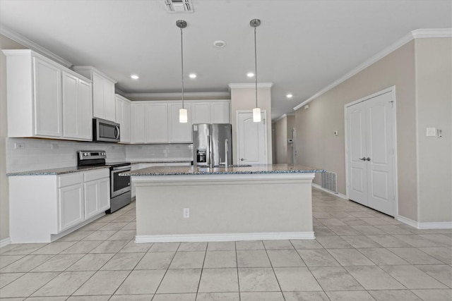 kitchen with appliances with stainless steel finishes, an island with sink, light tile patterned floors, and tasteful backsplash