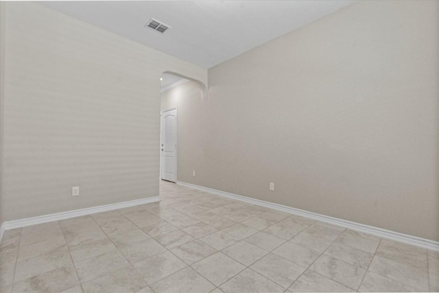 empty room with visible vents, arched walkways, and baseboards