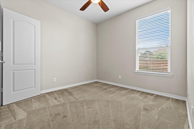carpeted empty room featuring baseboards and a ceiling fan