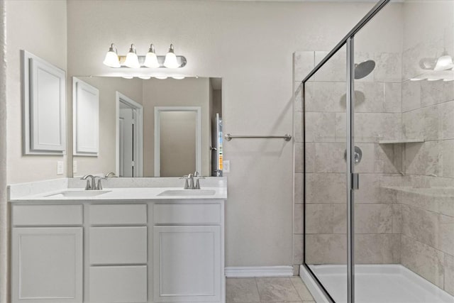 full bath with a sink, baseboards, a stall shower, and double vanity