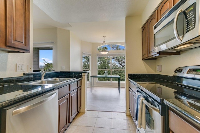6000 Shepherd Mountain Cv Unit 2007, Austin, TX 78730 - kitchen with appliances with stainless steel finishes, a sink, dark stone countertops, light tile patterned floors, and plenty of natural light